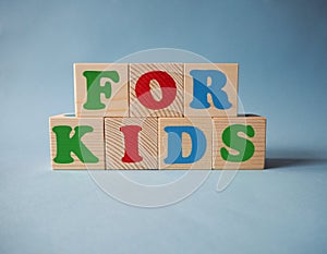 Wooden alphabet toy blocks with the text: For Kids.  kids ABC cubes on blue background with copy space