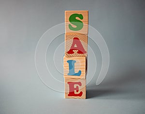 Wooden alphabet toy blocks with the text: sale. Isolated kids multi-colored ABC cubes on blue background with copy space