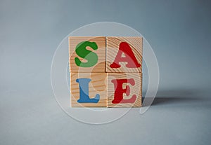 Wooden alphabet toy blocks with the text: sale. Isolated kids multi-colored ABC cubes on blue background