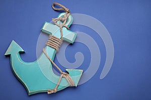 Wooden anchor figure on blue background, above view. Space for text