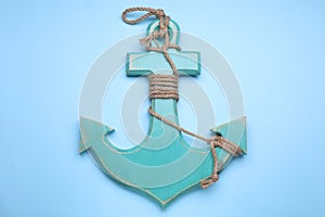 Wooden anchor with hemp rope on pale blue background, top view