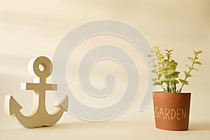 Wooden anchor in minimalist style with small tree in pot background