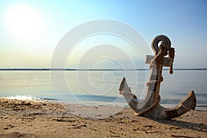 Wooden anchor on river shore near water