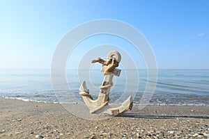 Wooden anchor with rope on sand near sea