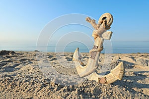 Wooden anchor with rope on sand near sea. Space for text