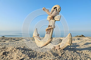 Wooden anchor with rope on sand near sea. Space for text