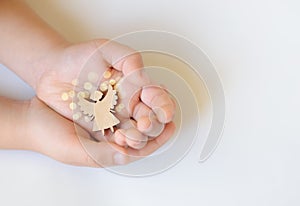 Wooden angel in children`s hands on a white background, celebration, dream