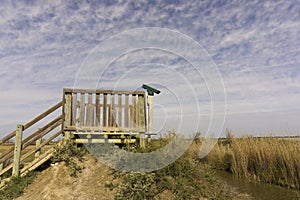 The wooden animal shelter and birding spotting scope camera, landscape of golden grass and small lake in pasture farmland