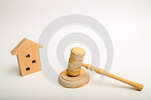 Wooden apartment house and hammer of the judge on a white background. The concept of the trial of an apartment building, the exami