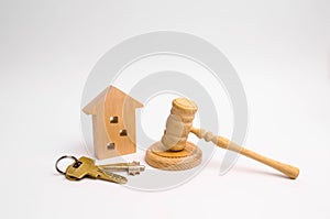 Wooden apartment house with keys and a judge hammer on a white background. The concept of the trial of an apartment house. Confisc