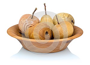 Wooden apples and pears in a fruit bowl made from a different types of wood isolated on white background with shadow reflection.
