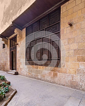 Wooden arabesque window, Mashrabiya, and door in stone bricks wall of ottoman old historic building