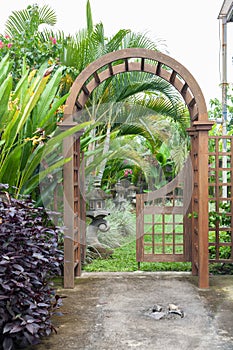 Wooden arbor with close on half gate in garden. Wooden arched entrance to the backyard.