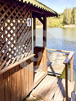 A wooden arbor with a pier by the water on the lake.