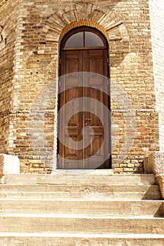 Wooden arch door in yellow brick water tower wall on sunny day