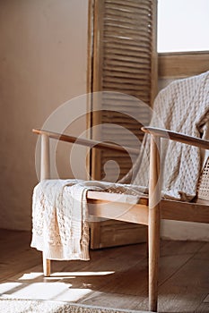 Wooden armchair with cotton knitted plaid in room