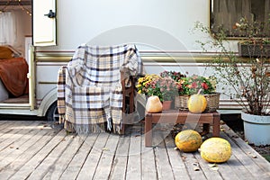 Wooden armchair near outside caravan trailer decorated for Halloween. Wooden RV house porch. Campsite in garden.