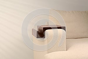 Wooden armrest table on sofa indoors, space for text. Interior element