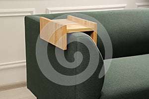 Wooden armrest table on sofa in room. Interior element