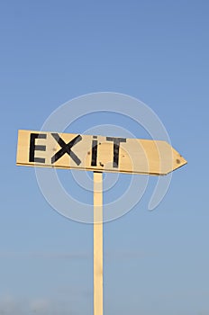 Wooden arrow sign with the word exit. In the background the blue sky.