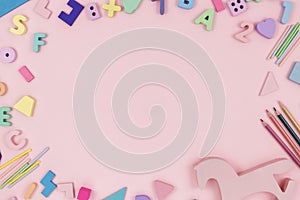 Wooden baby toys on a pastel pink background. Horse, numbers, blocks, puzzle shapes, pyramid, rainbow.