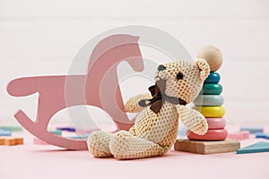Wooden baby toys on a pastel pink background. numbers, blocks, puzzle shapes, rainbow. Set of accessories for children.