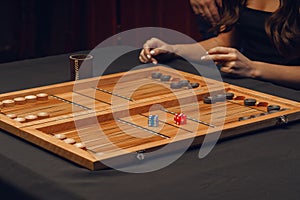 Wooden backgammon and girl`s hands with bones