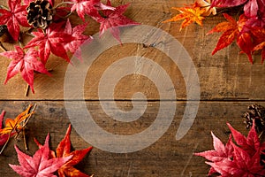 Wooden background with artificial autumn maple leaves.