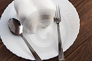 wooden background with a big tooth on a plate. a spoon and a fork