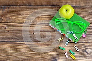 Wooden background with a book and glasses. Green apple. Top view