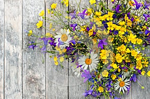 Wooden background with a bouquet of small wild flowers daisies, bells .