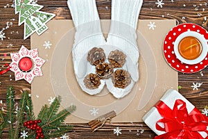 A wooden background with Christmas decorations. A woman in knitted mittens holds cones. Xmas card.New Year, holidays concept.