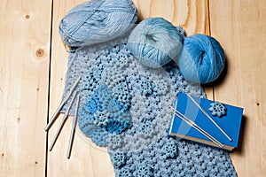 On wooden background elements of crochet, knitted blue lace napkins and knitting tools, balls of yarn and hooks. Hobbies in free