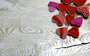 Wooden background with handmade felt hearts on light wooden background.