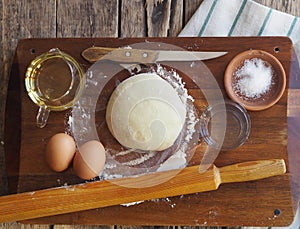 Wooden background with ingredients for making dough. Food and cooking utensils on a brown kitchen board. Place for text. The