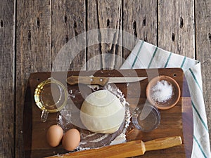 Wooden background with ingredients for making dough. Food and cooking utensils on a brown kitchen board. Place for text. The