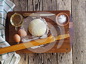 Wooden background with ingredients for making dough. Food and cooking utensils on a brown kitchen board. Place for text. The