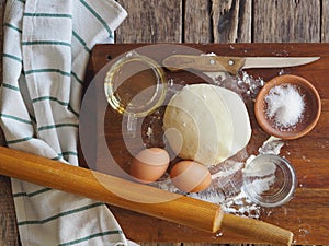 Wooden background with ingredients for making dough. Food and cooking utensils on a brown kitchen board. Place for text. The