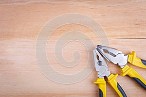 On a wooden background is a layout of various pliers. Top view.