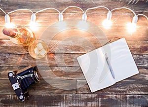 Wooden background with light garland, notebook and whisky