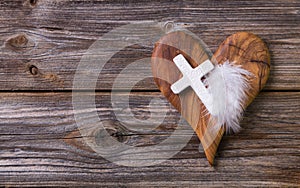 Wooden background with olive heart and white cross for an obituary notice. photo