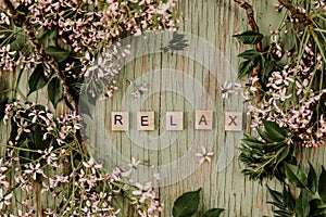 Wooden background with purple flowers surrounding wooden letters with the word relax