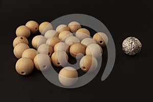 Wooden balls and silver ball on black background