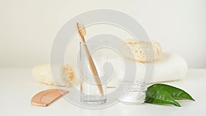 Wooden bamboo toothbrush falls into glass and bathroom zero waste products on a white background