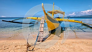 A wooden banca anchored on the beach of a tropical island in the Philippines. photo