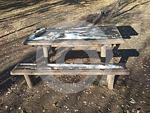 wooden banch and table partly covered by snow
