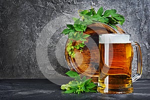 Wooden barrel of craft beer with glass mug and hops in dark cellar