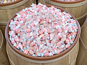 A wooden barrel full of large quantity of wrapped strawberry flavored taffy