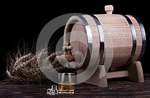 Wooden barrel with rye crops close up with black background