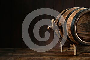 Wooden barrel with tap on table near wall.